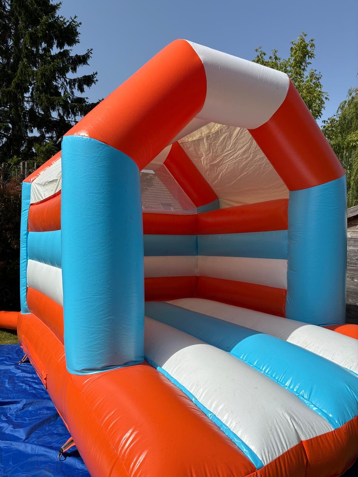 Château gonflable orange, bleu et blanc installé en extérieur, en location pour anniversaire d’enfants près de Douai