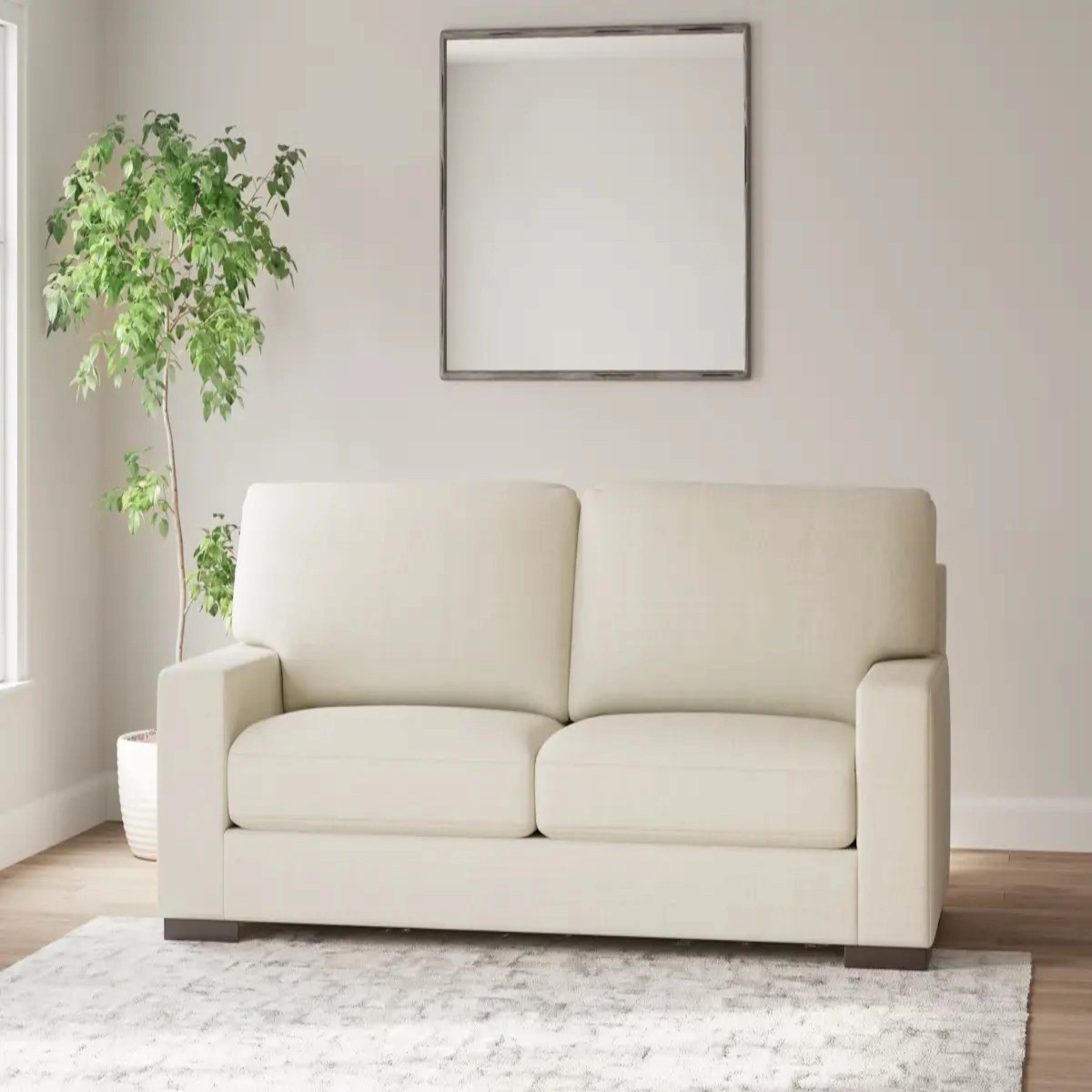 Cream Ashley Furniture sofa in a bright room with a plant and wall mirror