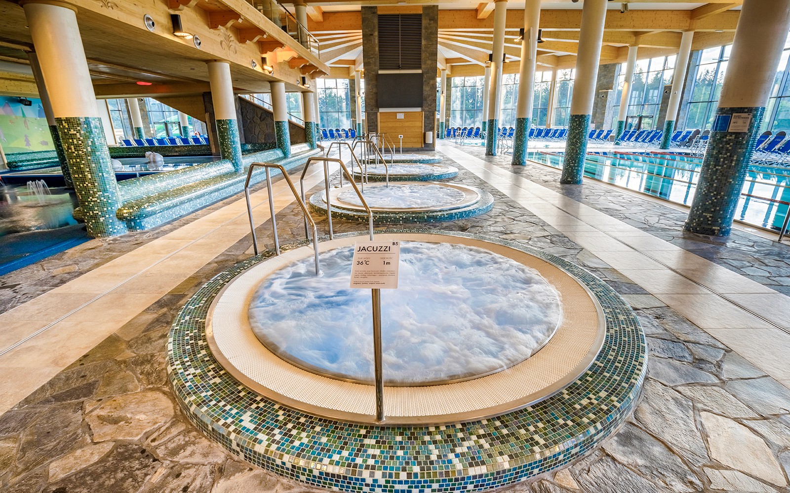 Jacuzzi area inside Chocholow Thermal Baths with tiled floors and large windows.