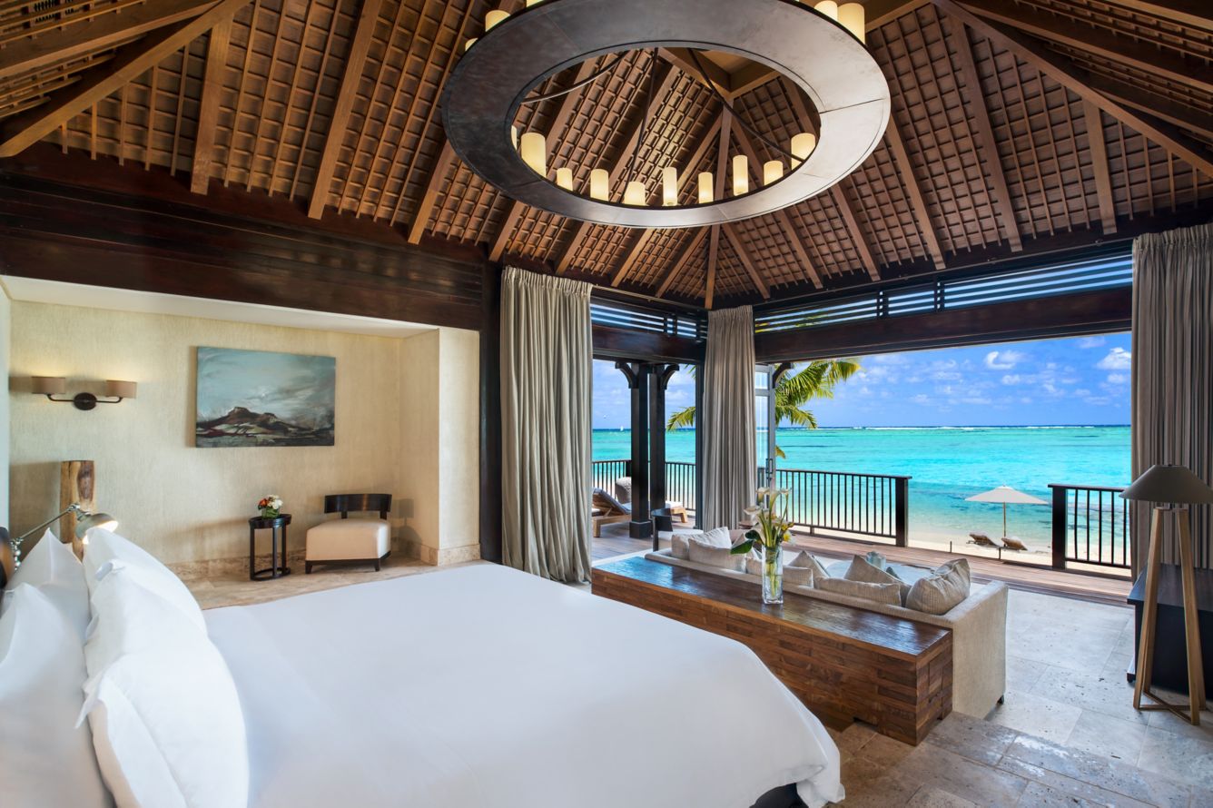 Helle, luxuriöse Hotelsuite mit Kingsize-Bett, Holzbalkendecke und direktem Zugang zu einer privaten Terrasse mit freiem Blick auf den Indischen Ozean.