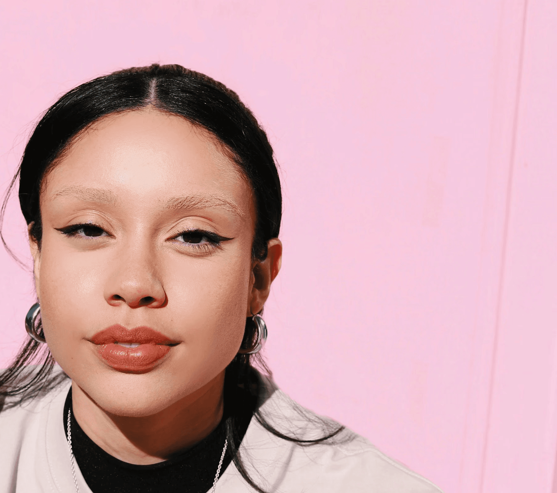 a woman sitting at a table in front of a pink wall