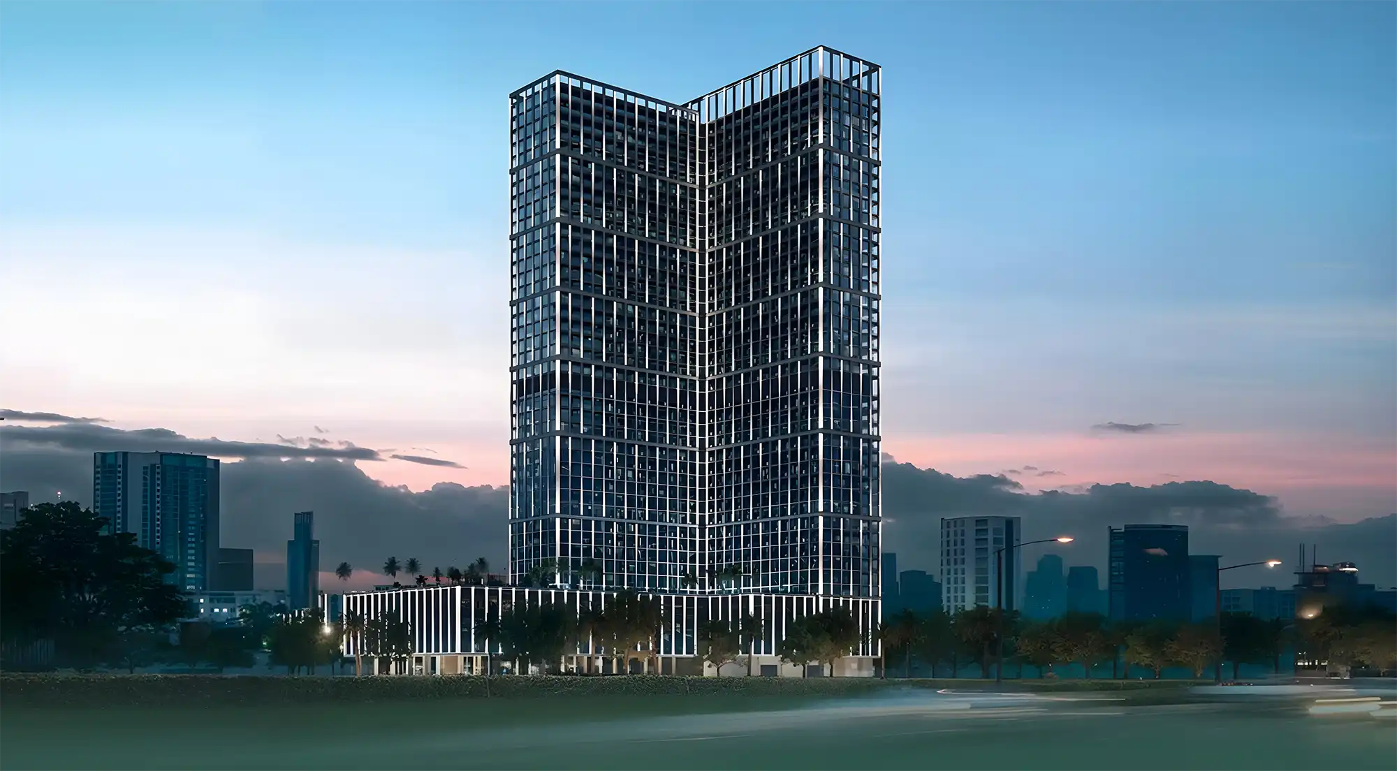 Binghatti Vintage, a tall building with many windows, stands out at night, glowing against the evening backdrop.