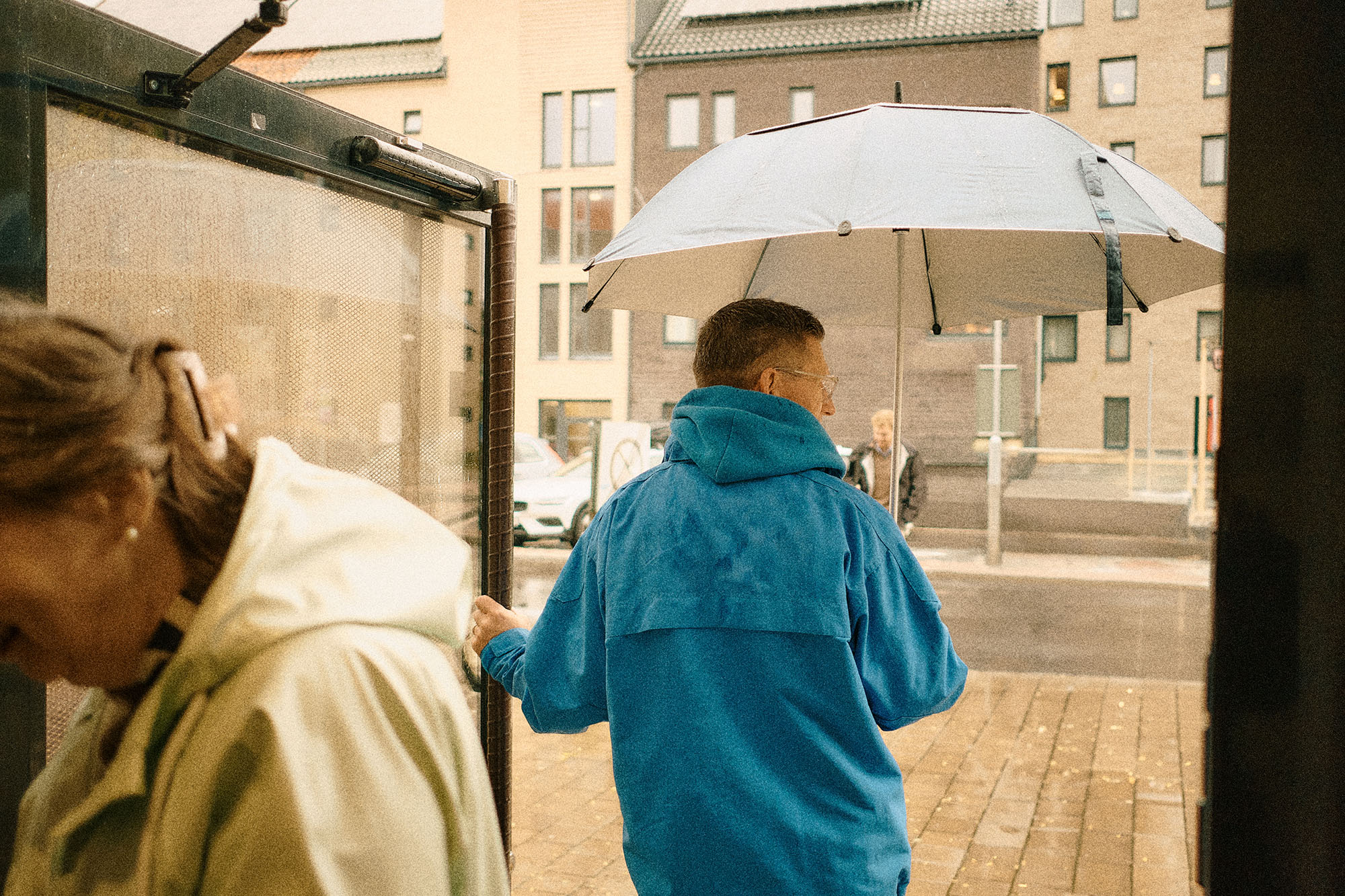 En person med glasögon och kort hår som står inne i en träningshall. På väggen hänger fyra pilatesbollar på en ställning.