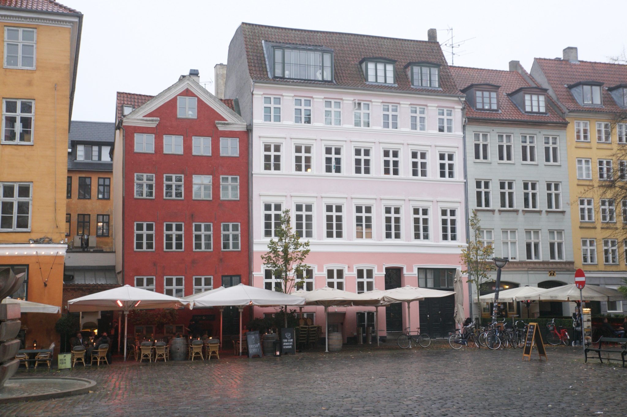 Colourful row of Nyhavn townhouses with outdoor umbrellas and bicycles parked outside