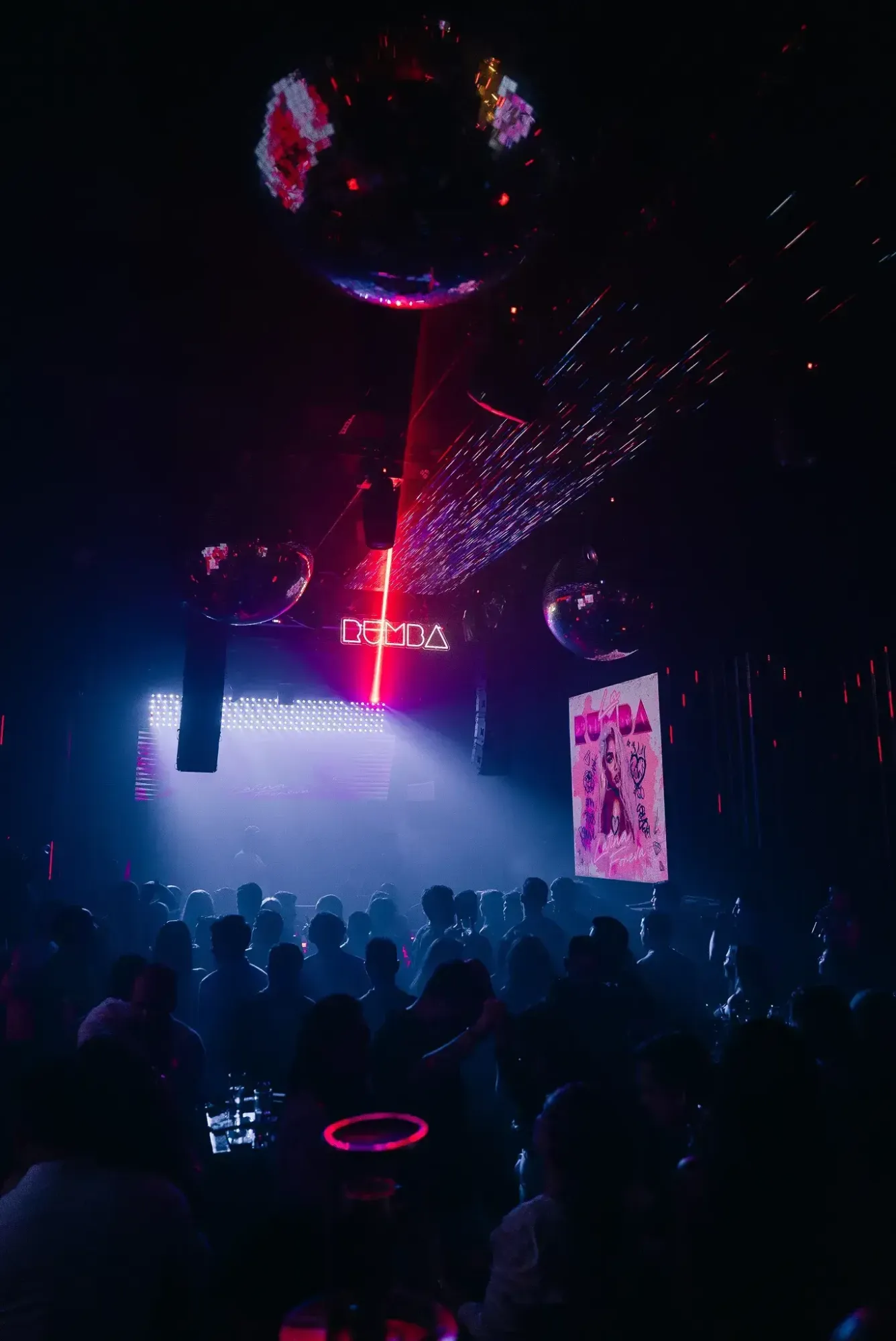 Rumba neon sign above the DJ booth and a crowd in blue haze at The Myth Dubai