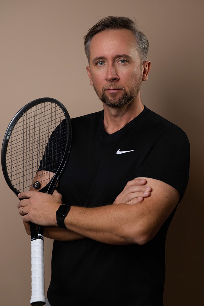 man in white crew neck t-shirt and black pants sitting on brown wooden fence during