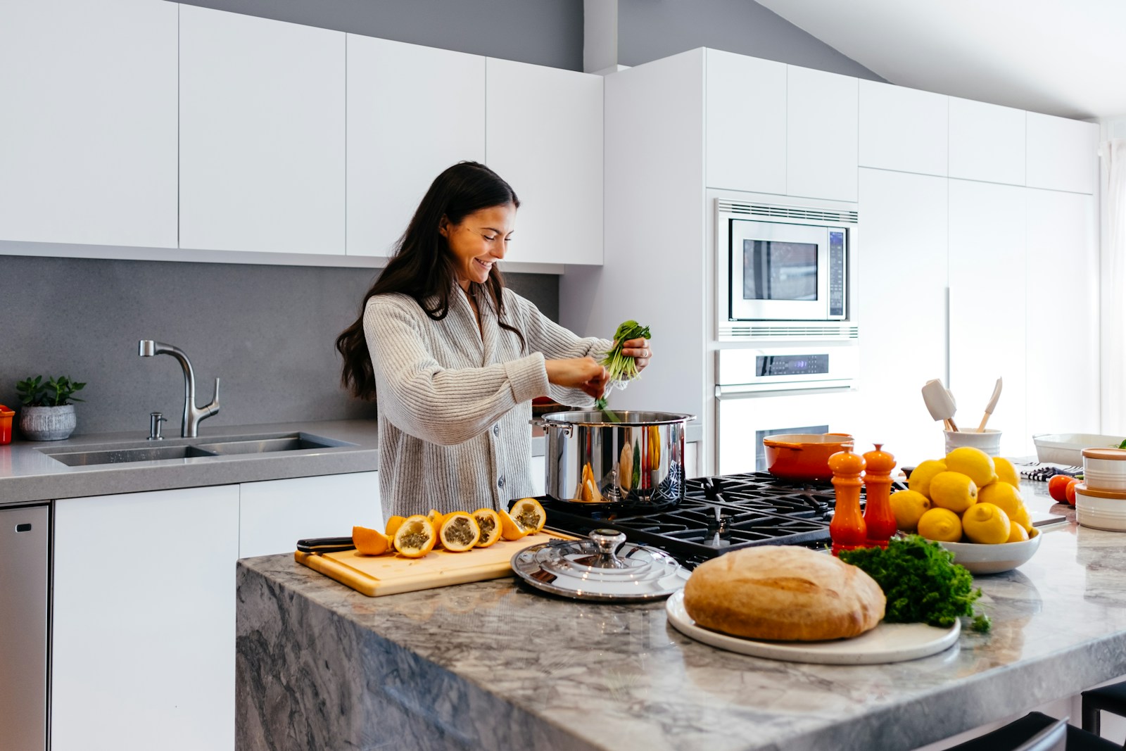 A smiling woman cooking a fresh, healthy meal in her kitchen after starting nutrition counseling