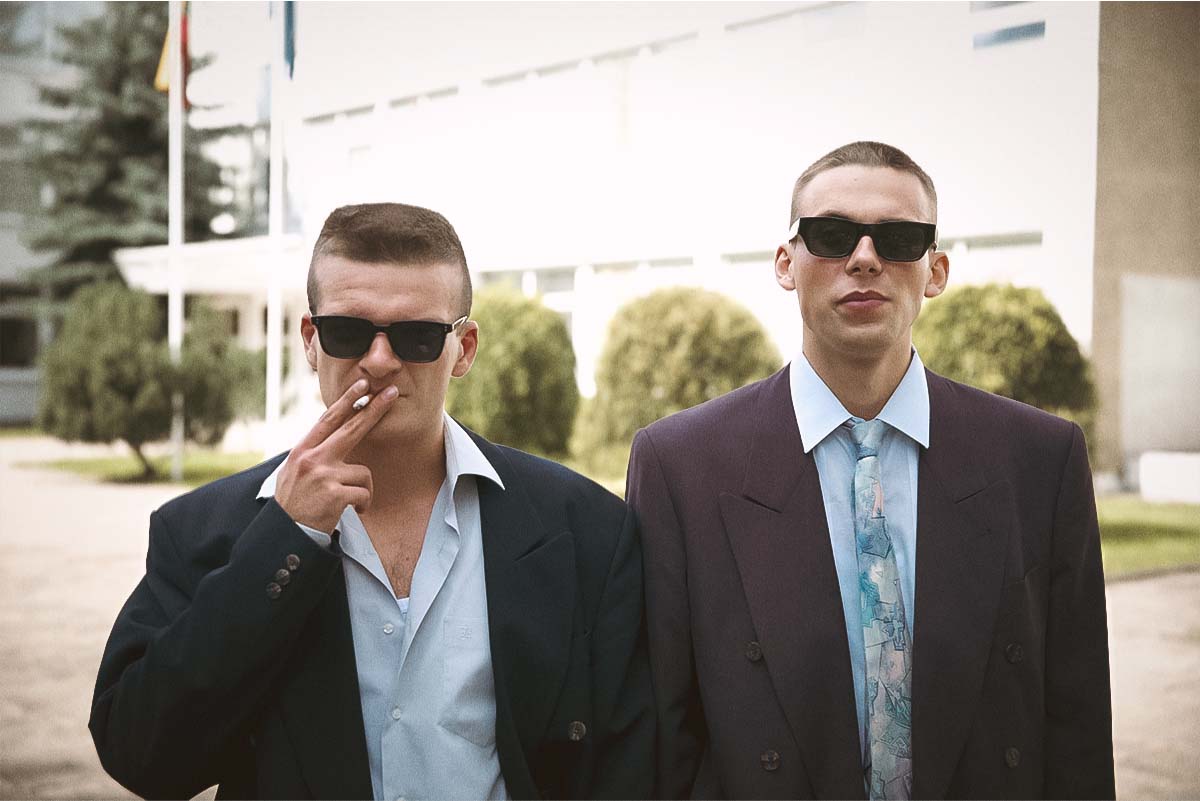 Džiugas Grinys as Rimants and Robertas Petraitis as Mindė standing confidently in sunglasses in Lithuania’s Oscar-nominated 90s comedy-drama Southern Chronicles (Pietinia Kronikas).