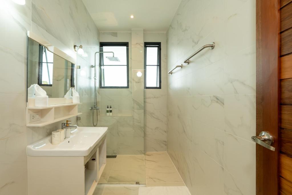 A sophisticated lounge terrace with curved white stucco walls, stone seating, and arched cutouts perfectly framing an unobstructed ocean sunset.