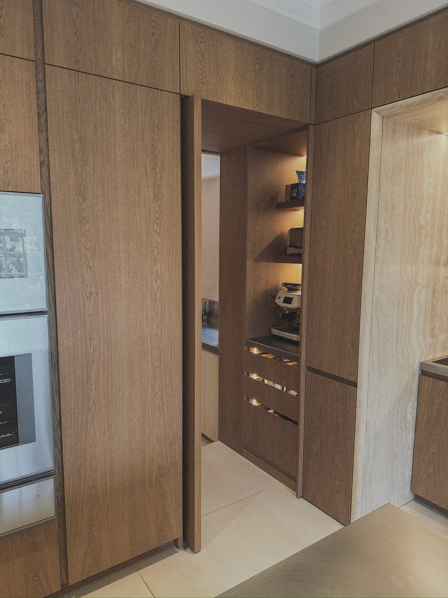 Bespoke oak pivot door with joinery with integrated shelving and pullout drawers with led lighting