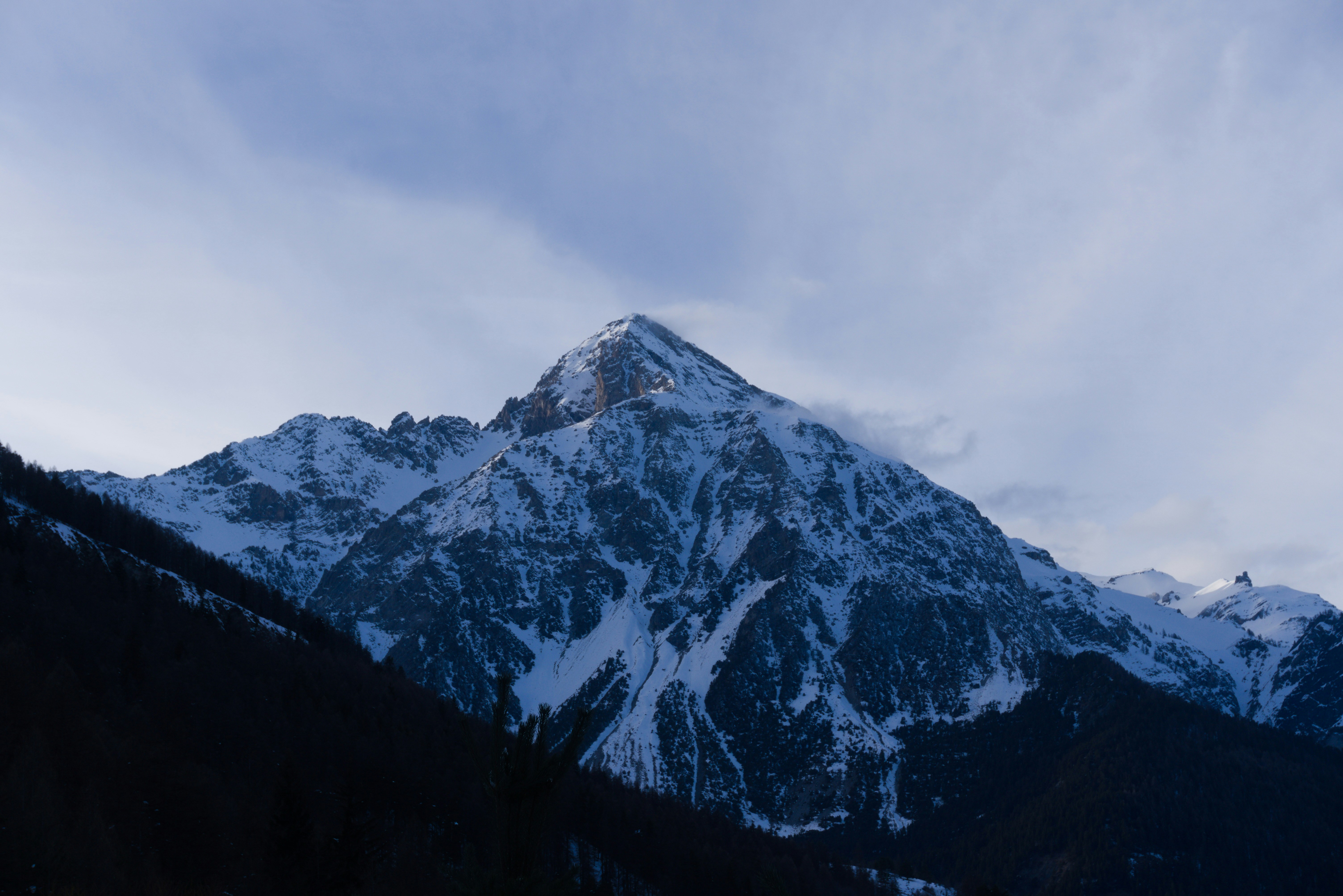 A mountain covered in snow under a cloudy sky