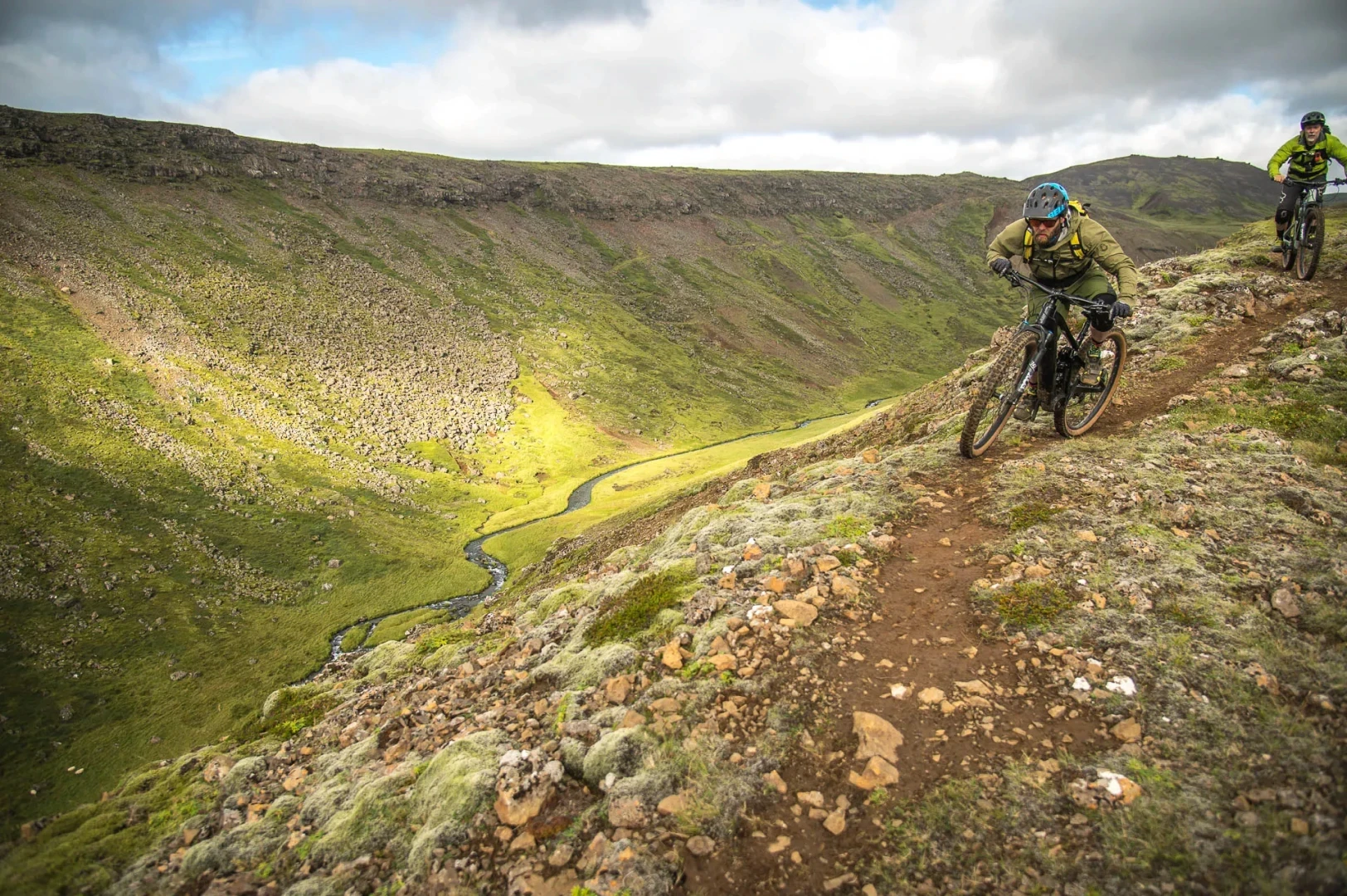 two men ride mountainbikes down a mountain in a geothermal area 
