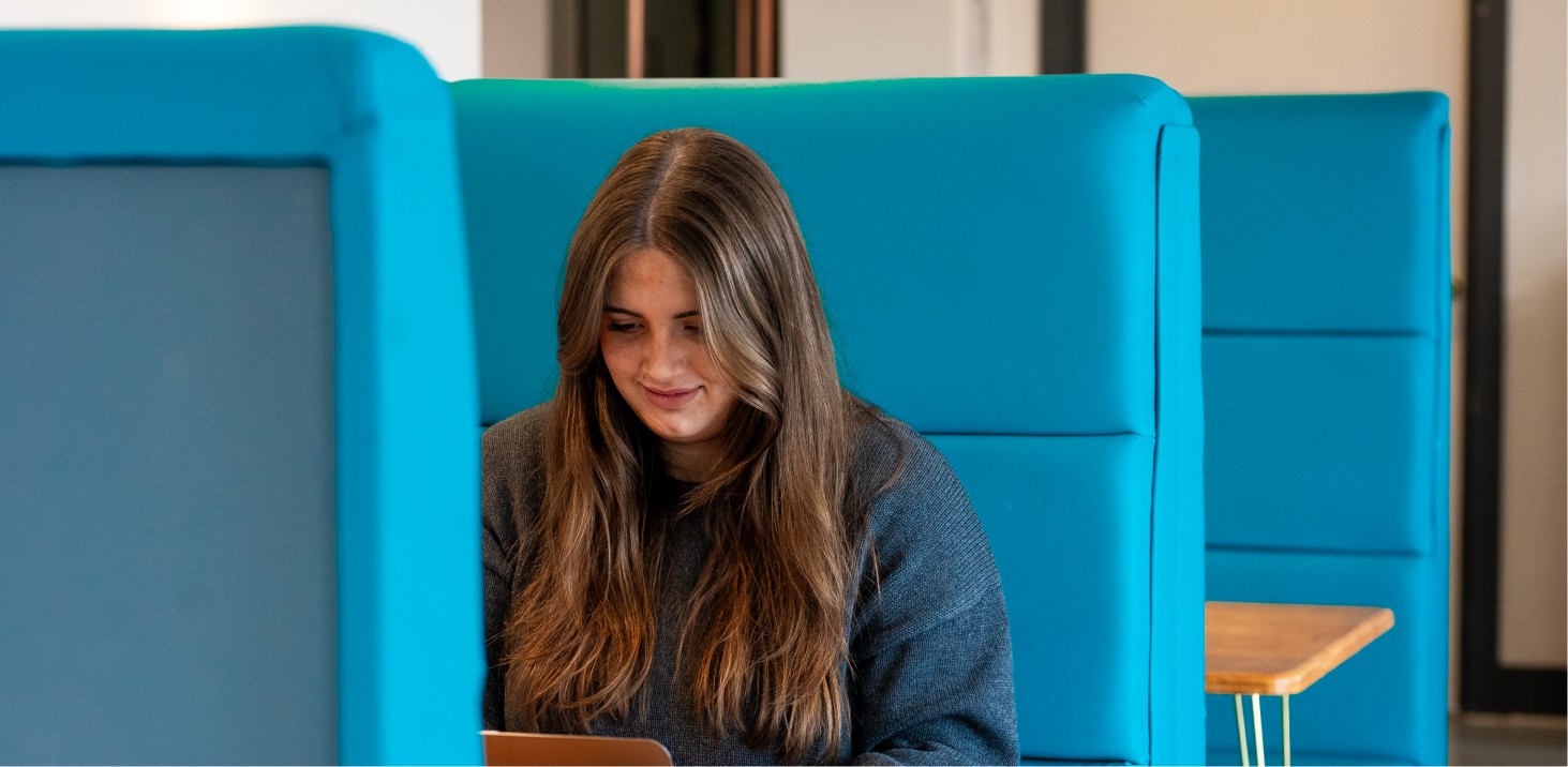 Person sitting on blue benches looking at a small box.