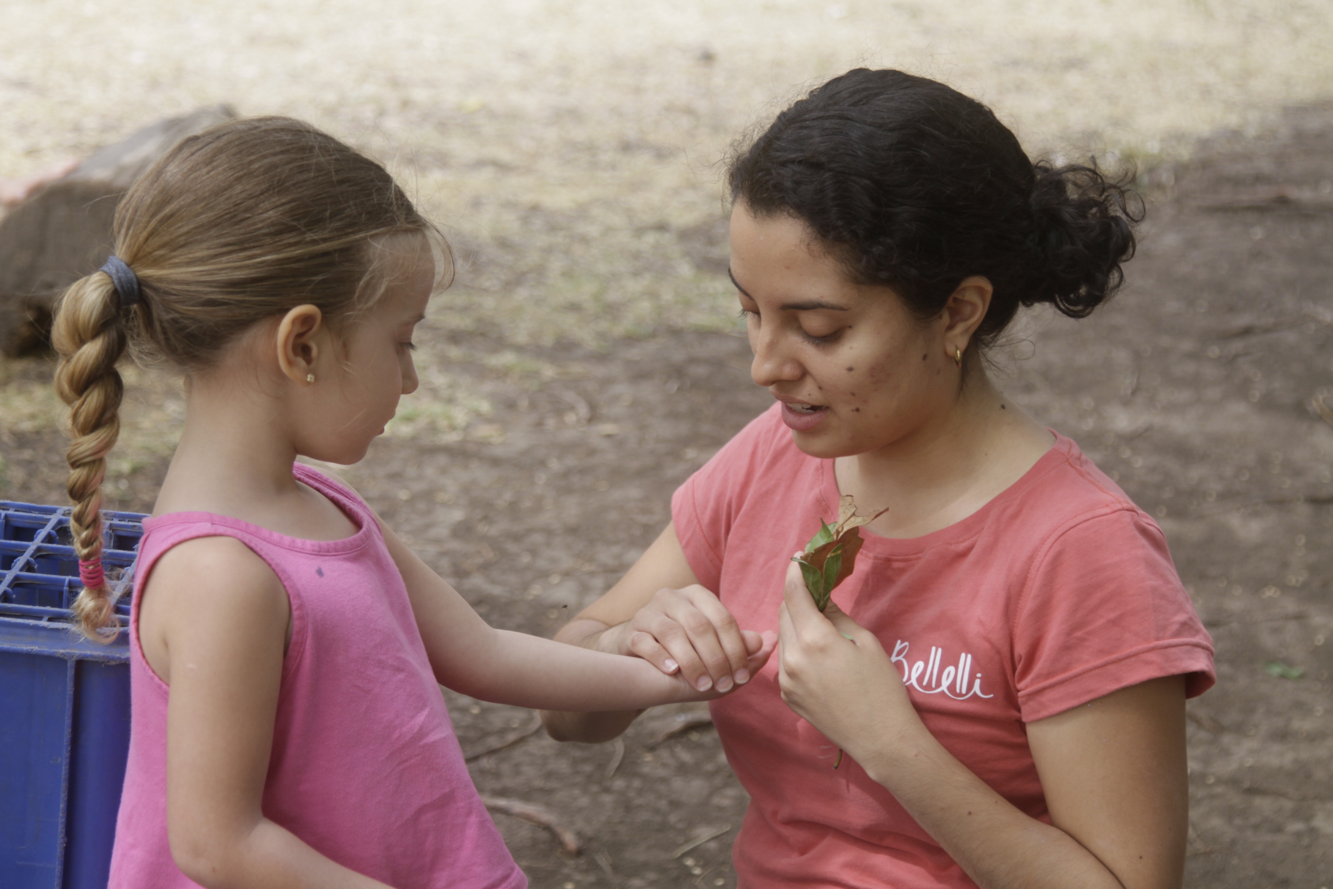 Maestra o guía explicando algo a una niña en un entorno natural, enfatizando la interacción educativa