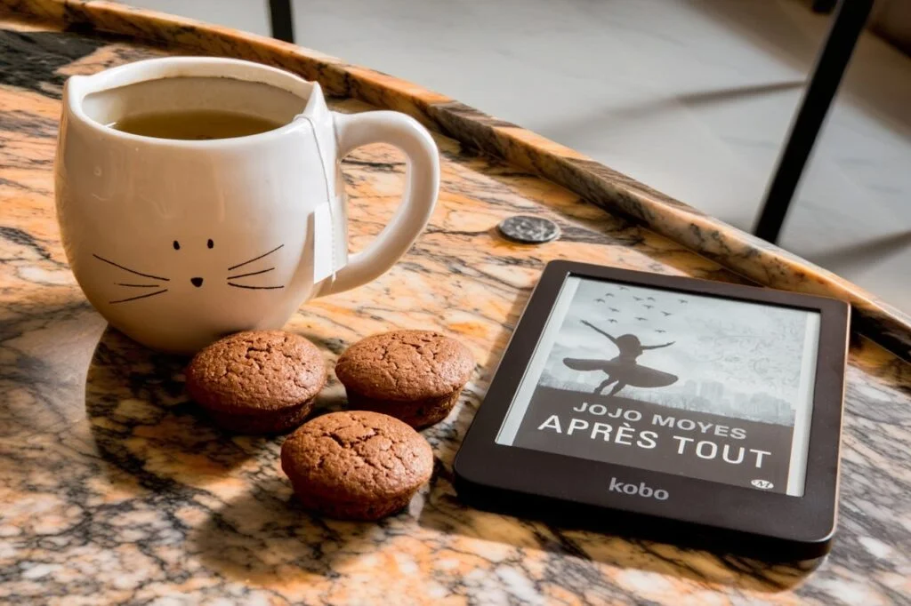 A cup of coffee with ginger biscuits and a reading tablet