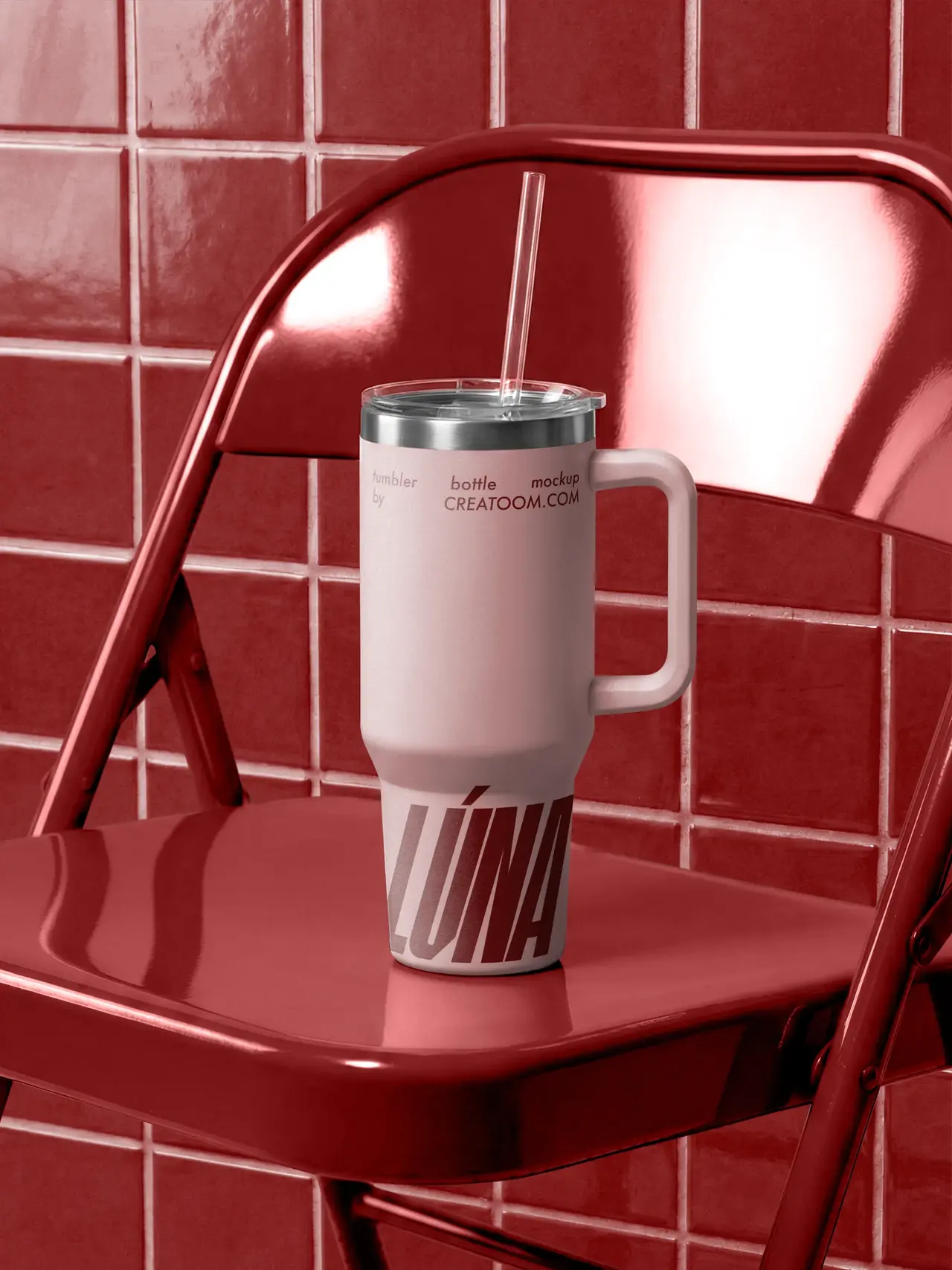 Pink tumbler with a straw on a red chair against a tiled wall.