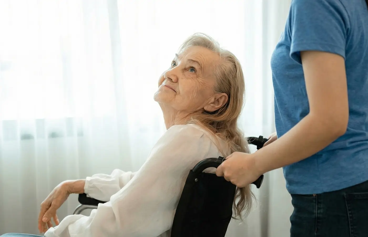 Caregiver providing consistent presence to a senior in a wheelchair at home