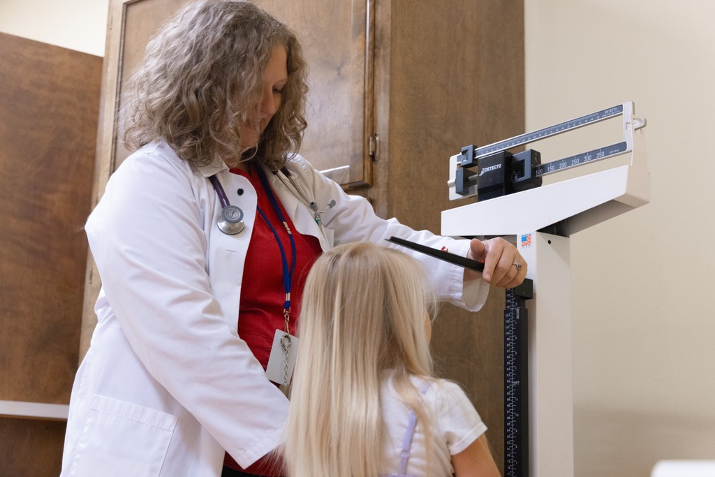 Pediatrician measures the height and weight of a young patient.