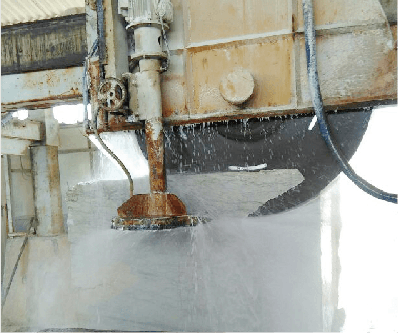 Close-up of the cutting process with the Dinosaw Vertical Plus Horizontal Cutting Machine, showing water-cooled blades slicing through a stone block. The precision and efficiency of the machine are evident in its clean cuts and smooth operation.