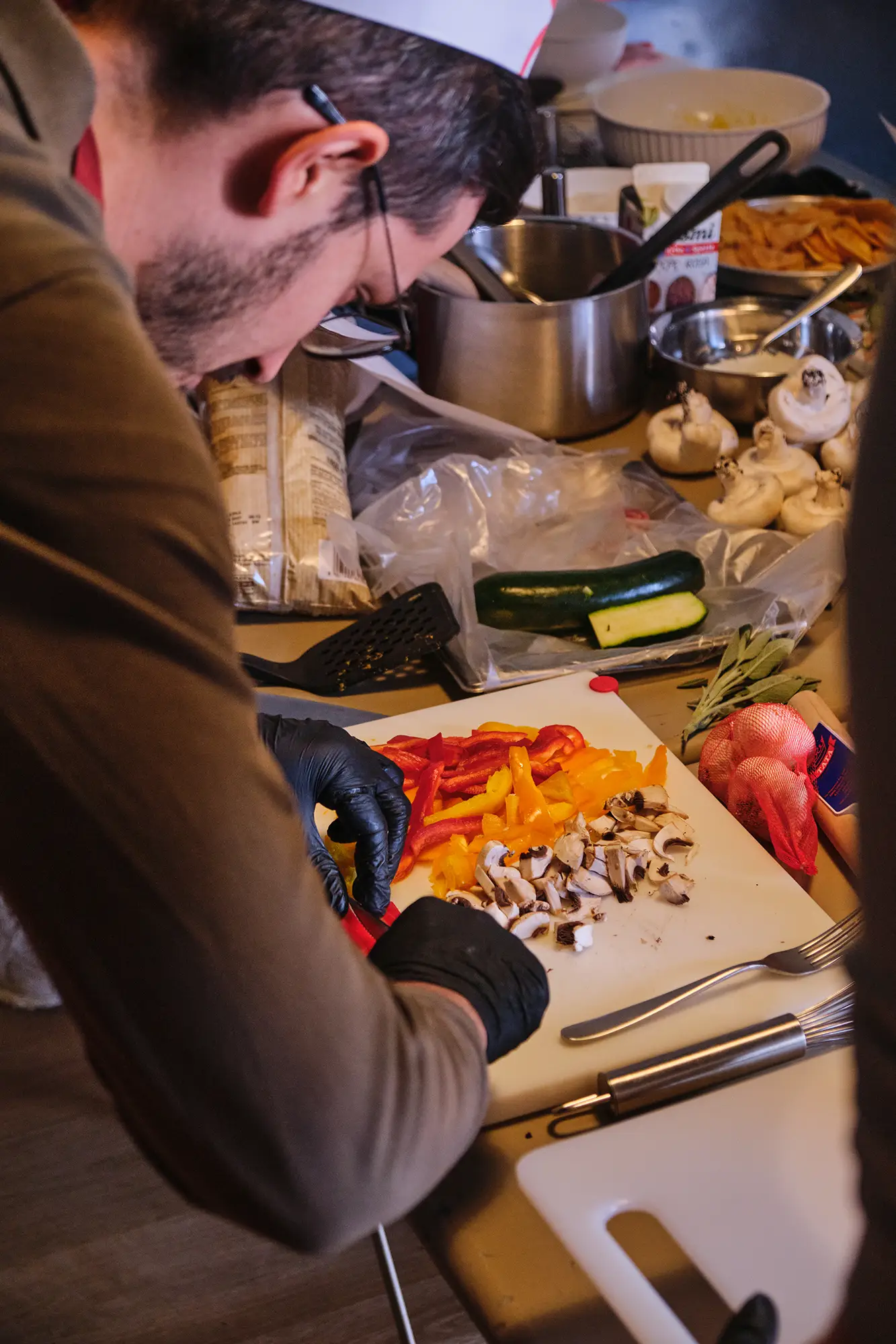 Postazione di lavoro: colleghi di Reka al bancone con verdure, zucca e couscous durante la sfida mystery box.