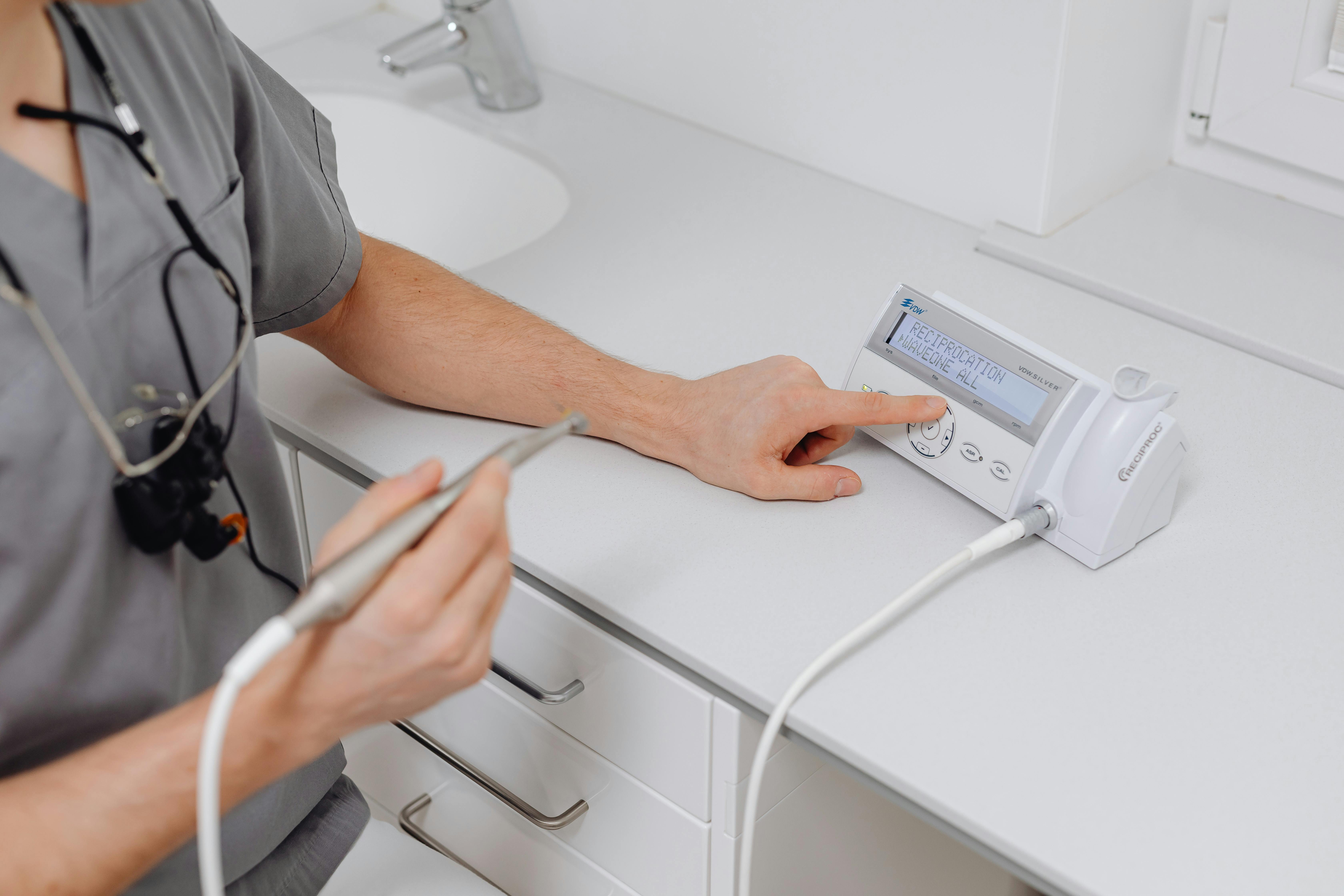 A picture of Dental professional operating endodontic motor device in clinic.