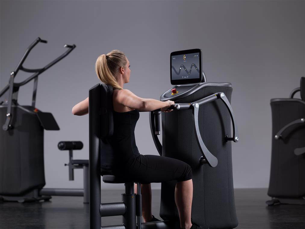 A person exercises using fitness equipment in a minimalist gym setting, focused on their workout.