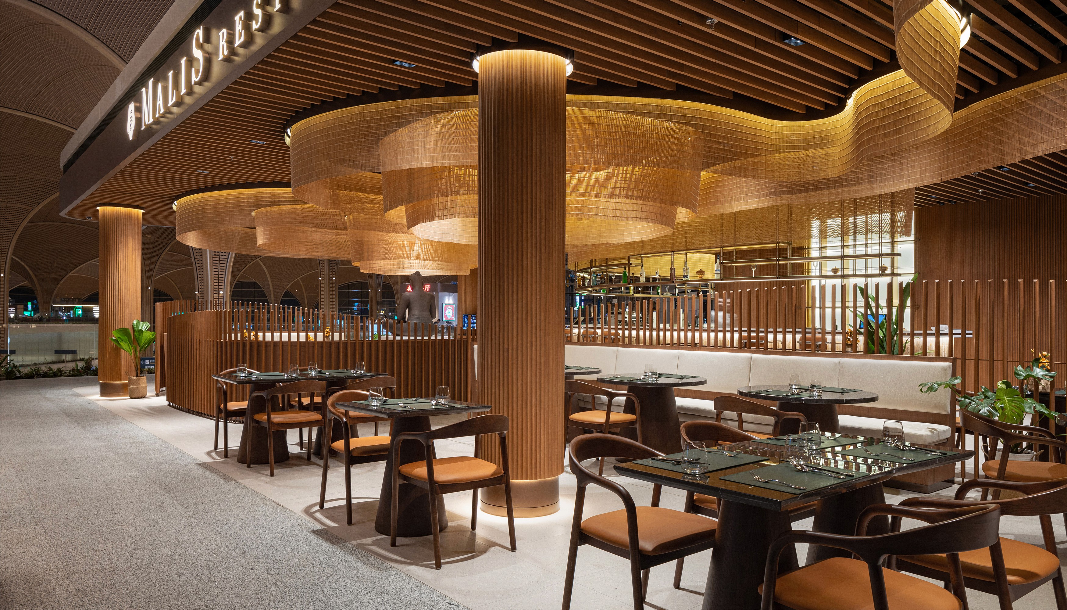 Entrance view showing the complex timber slat ceiling and integrated signage of Malis Restaurant reflecting the rigorous technical standards and documentation required for high-traffic public spaces