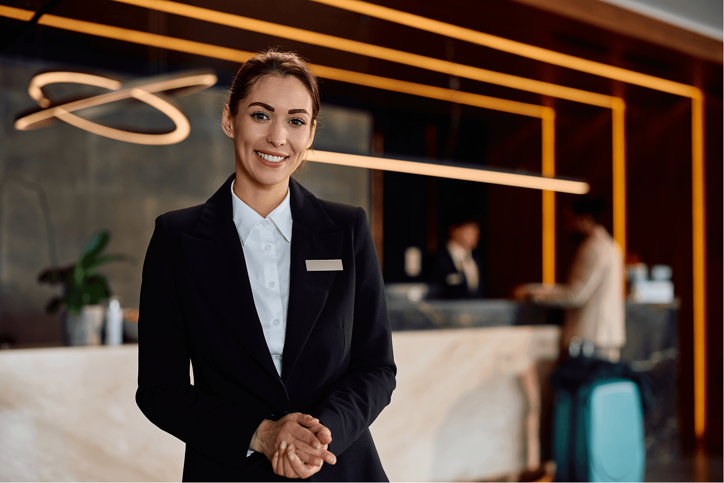 Image of a hotel staff member welcoming guests at a reception desk in a hospitality and tourism video.