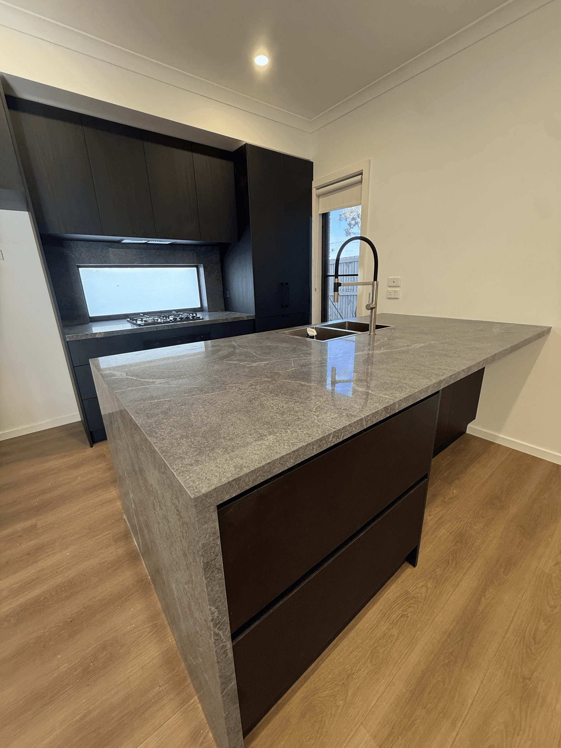 Finished kitchen with stone island benchtop and downlights installed by Delca Electrical