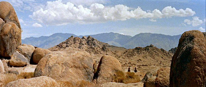 A person walks down a dimly lit alley at night.