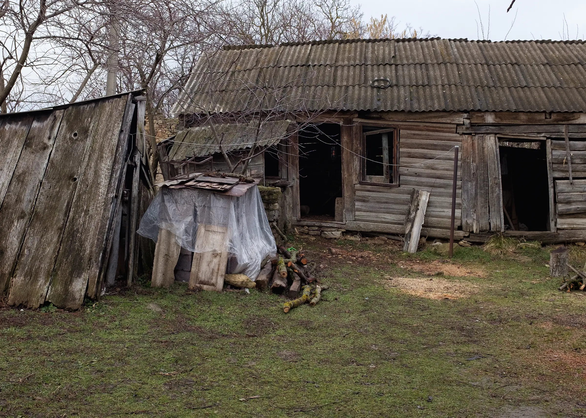 Abandoned wooden house with firewood pile outside.