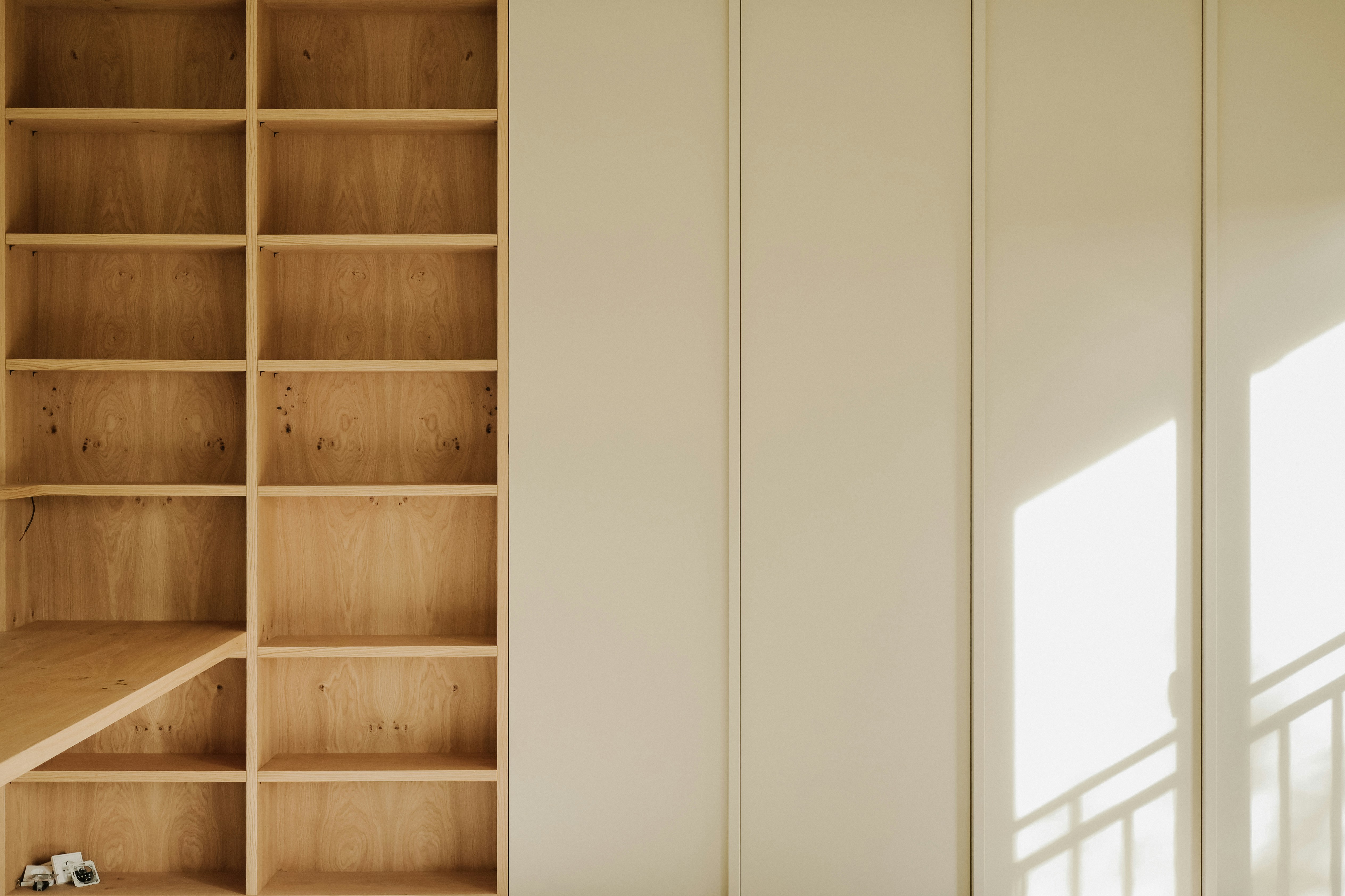 Empty wooden bookshelves and cream colored wall