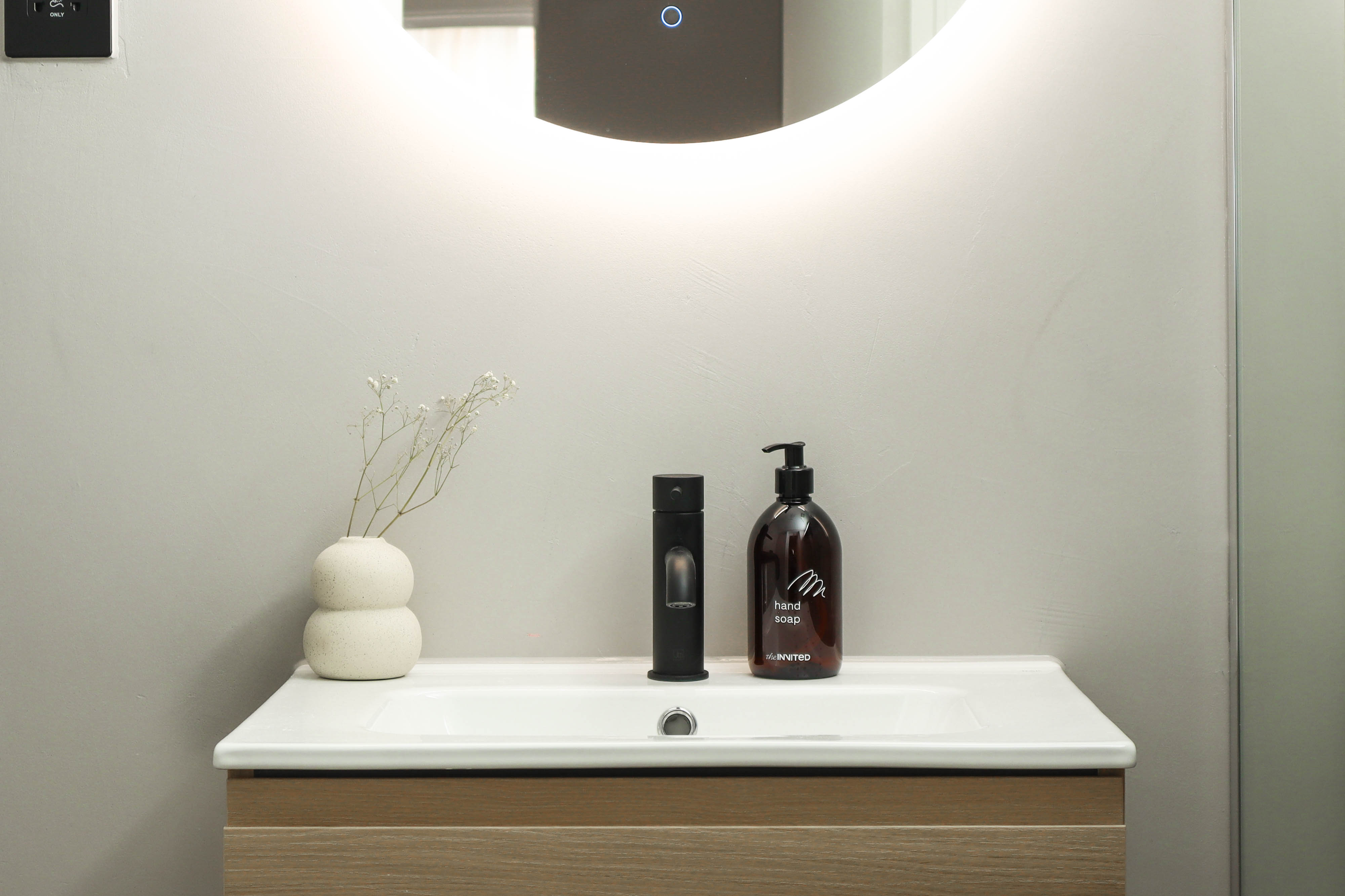 Bright modern bathroom with minimalist vase and backlit mirror