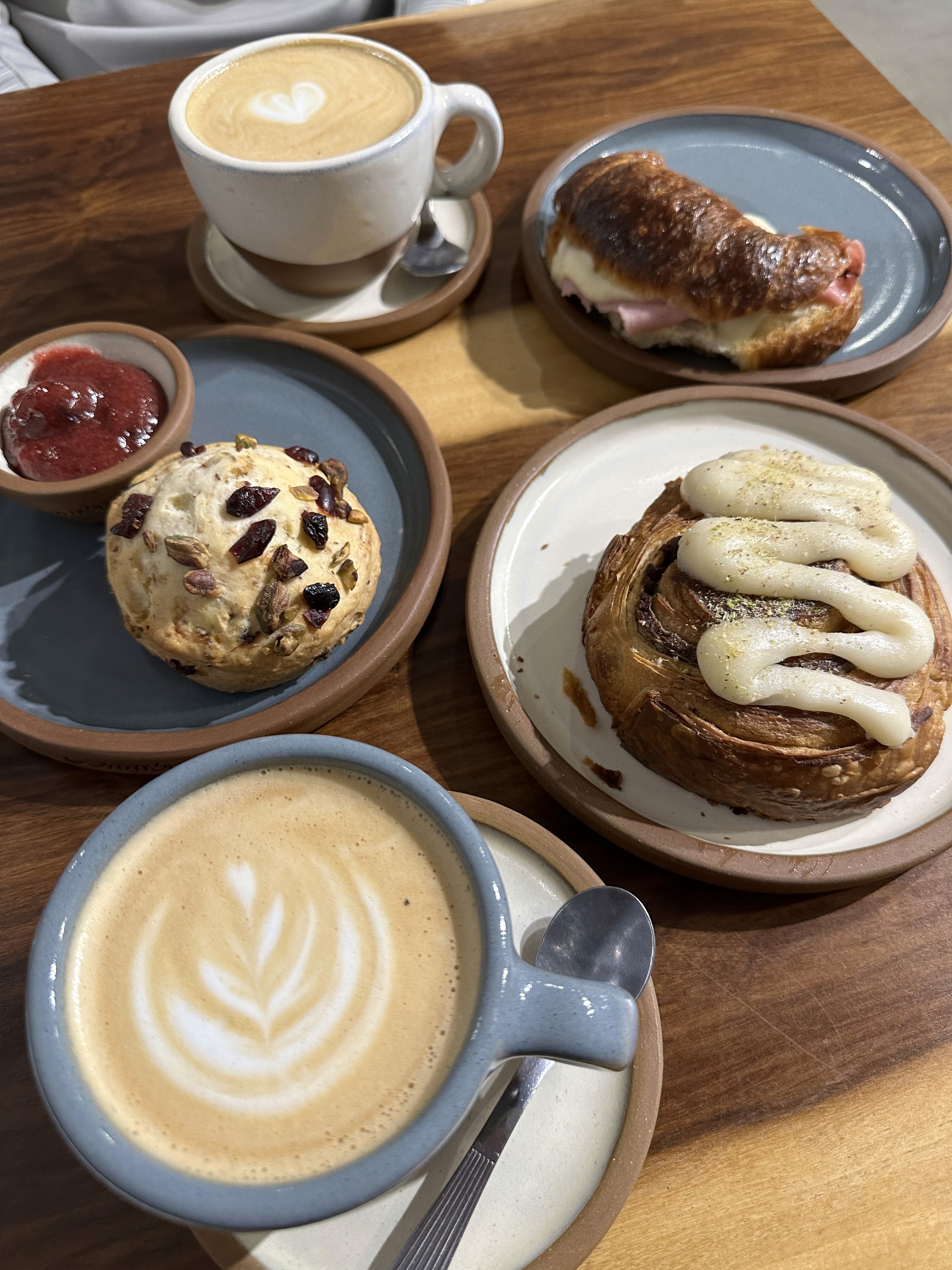 A latte with leaf-pattern foam art next to a plate of pastries.
