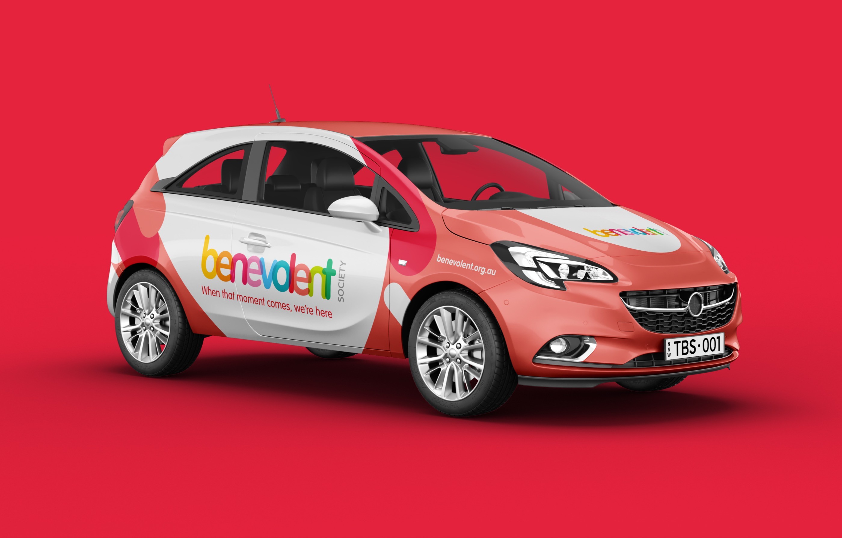 Rendered mockup of a red hatchback car with Benevolent Society vehicle livery, showing the logo and tagline "When that moment comes, we're here" on the door.