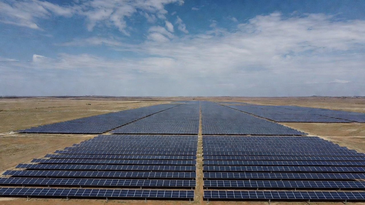 Aerial view of a hydroelectric dam spanning a turquoise river surrounded by dense forest and winding roads
