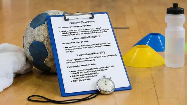 Training-plan clipboard beside a handball, cones, stopwatch and water bottle on an indoor court.