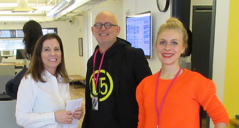 A photo of three people standing in an office.
