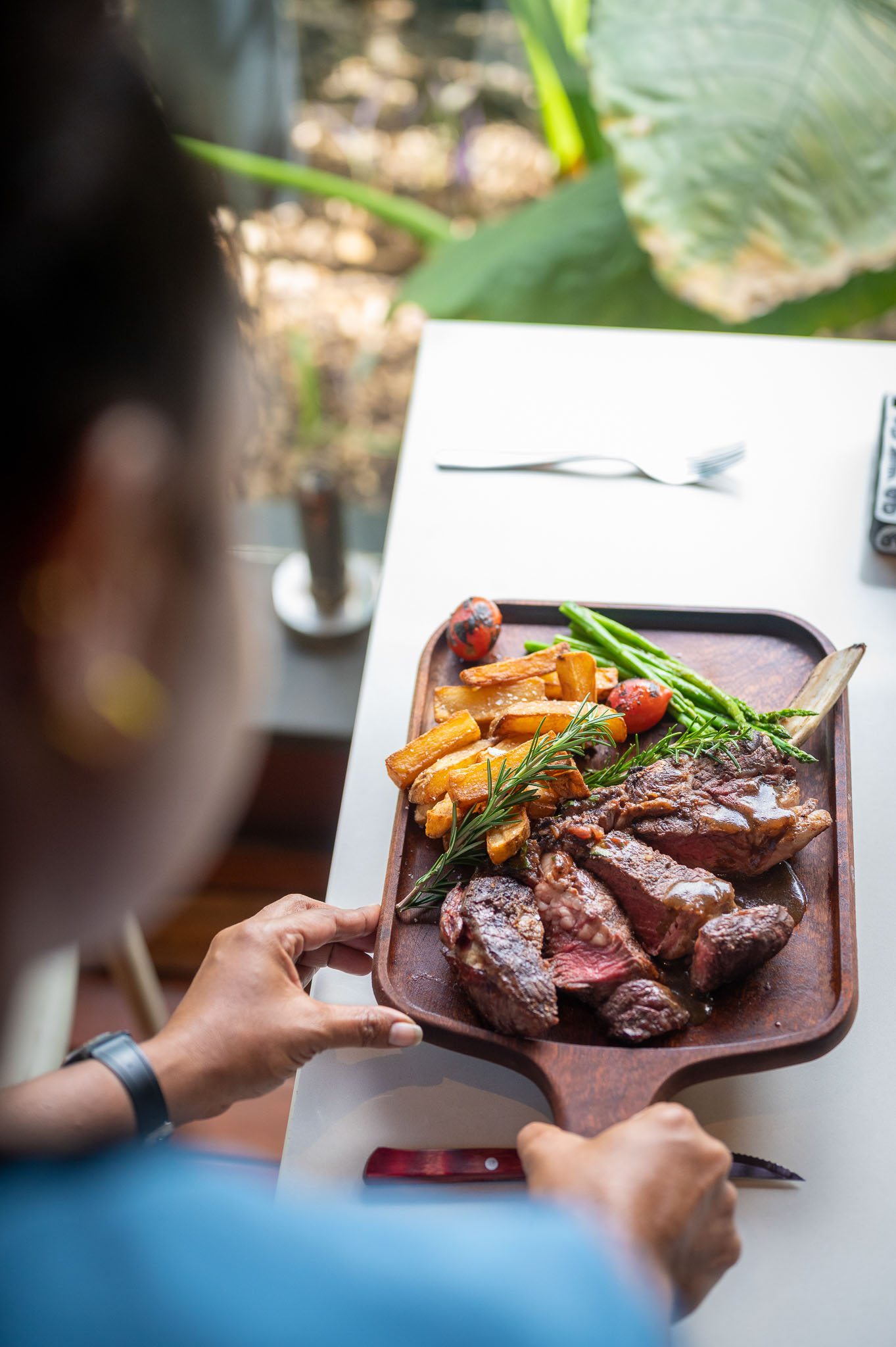 Close-up of a juicy steak served with grilled vegetables and fries, with a customer about to take a bite