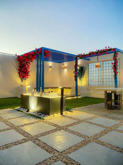 A modern outdoor space featuring patterned tiles, colorful canopies, and soft lighting, set against a twilight sky.