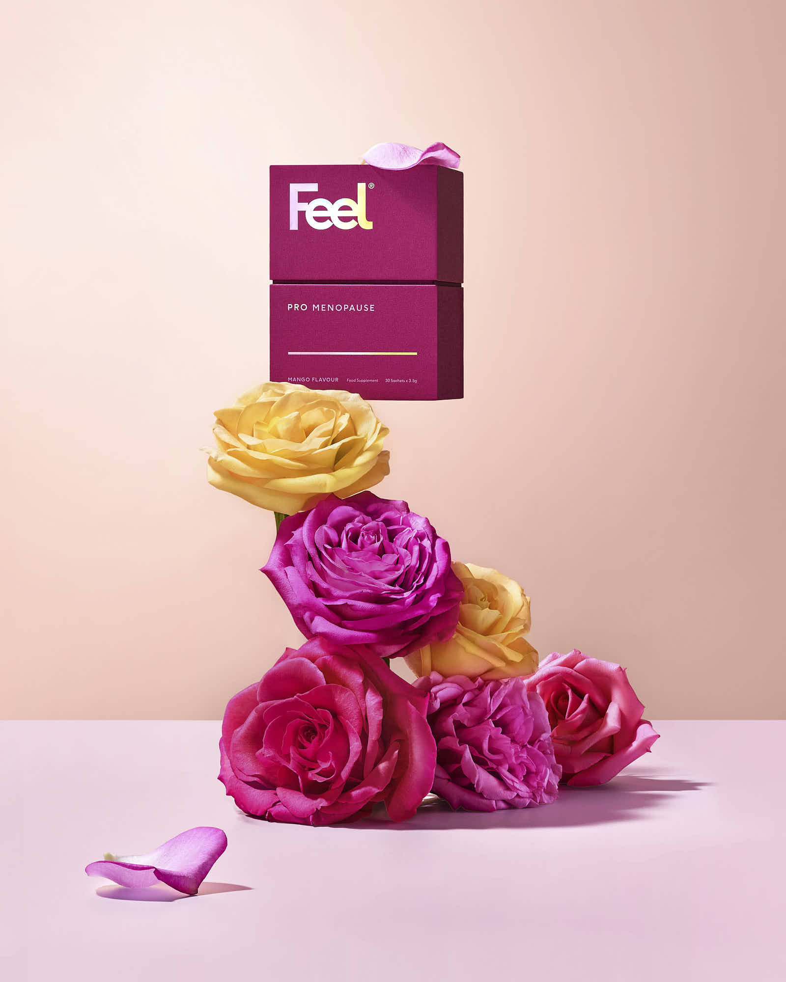 Colorful rose flowers arranged with a bright packaging, set against a soft pink background.
