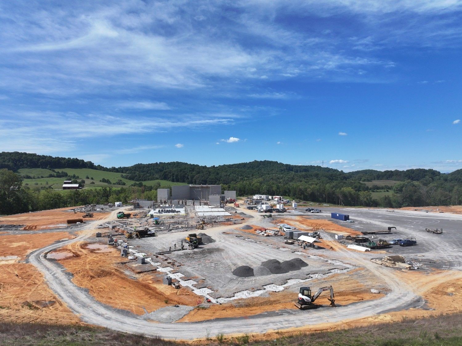 Aerial shot of large construction site with grading, gravel and partially constructed block walls with contruction materials and equipment.