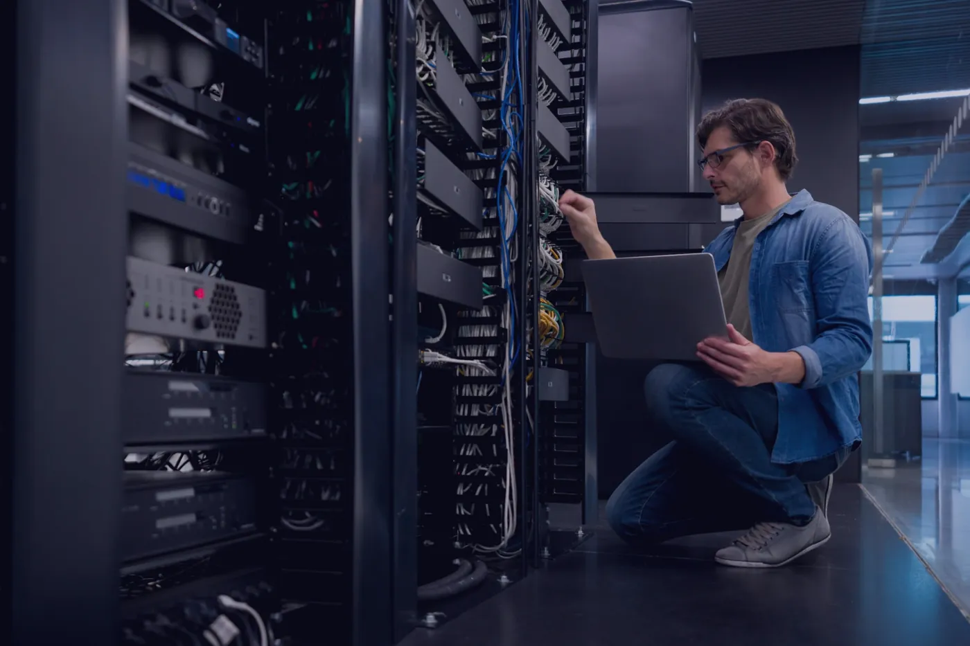 Technician handling server equipment during data center relocation and infrastructure setup