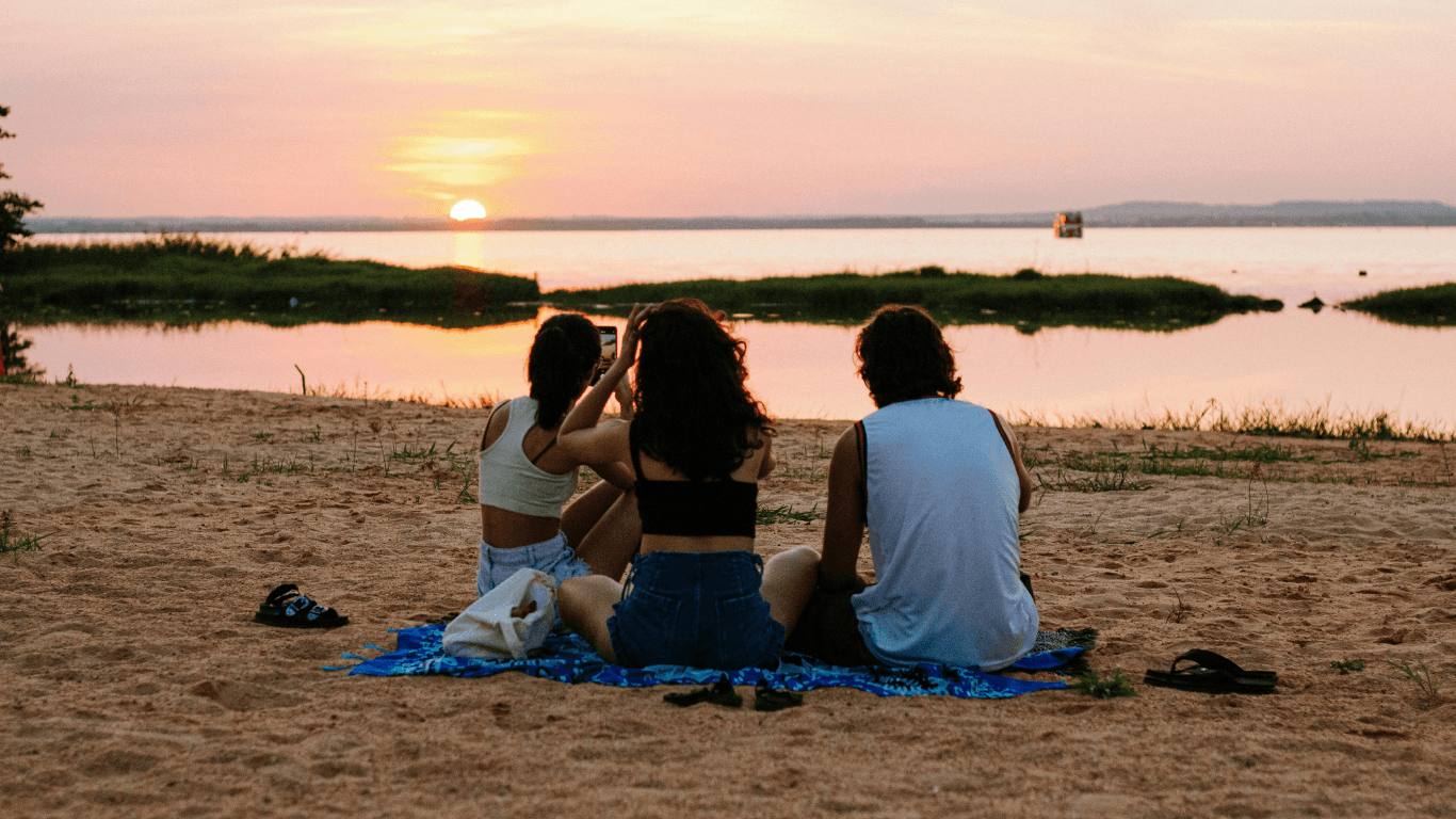 Three roommates relaxing together at sunset on the beach