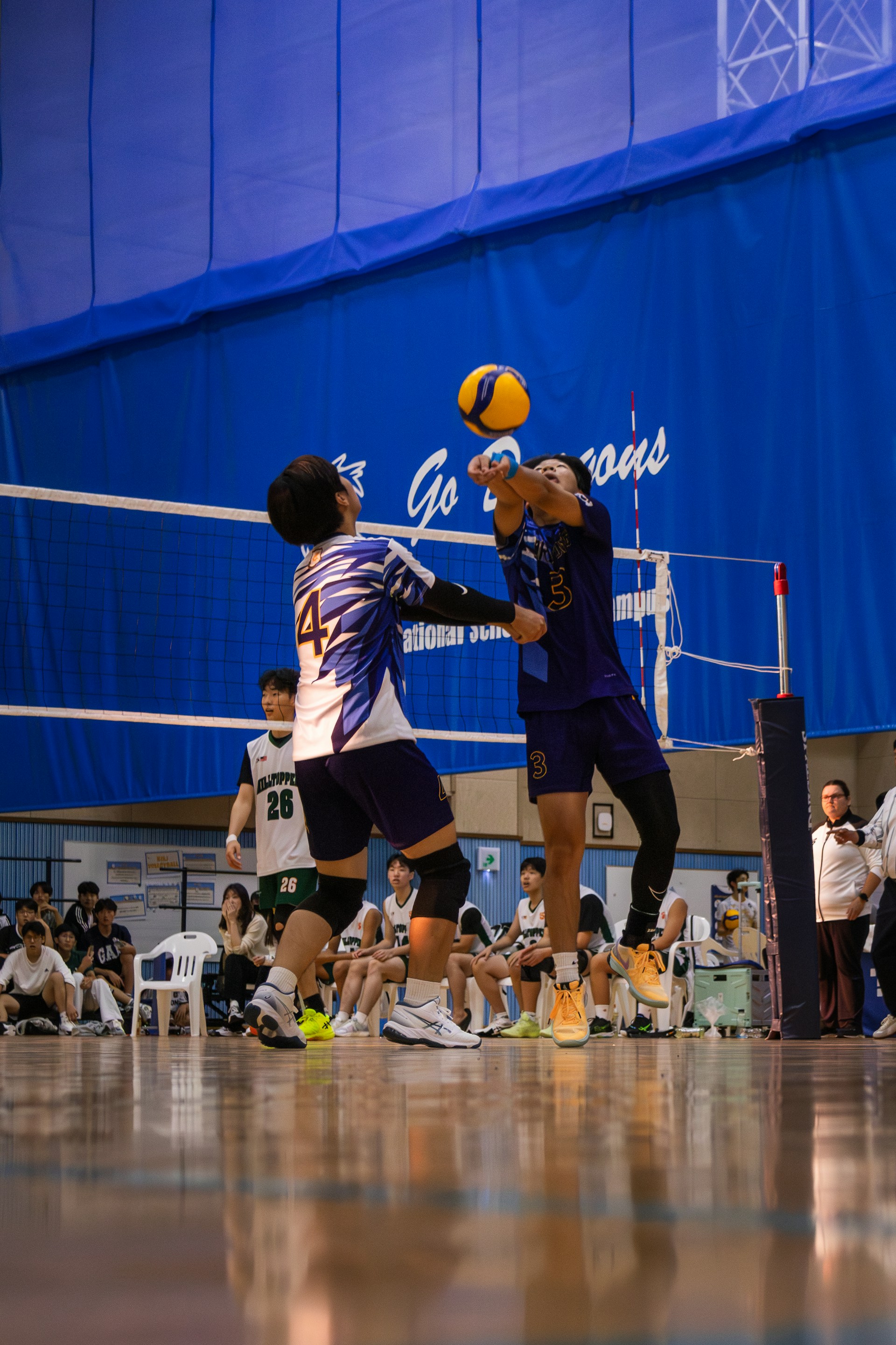 Two volleyball players jumping at the net to contest the ball during a joust.