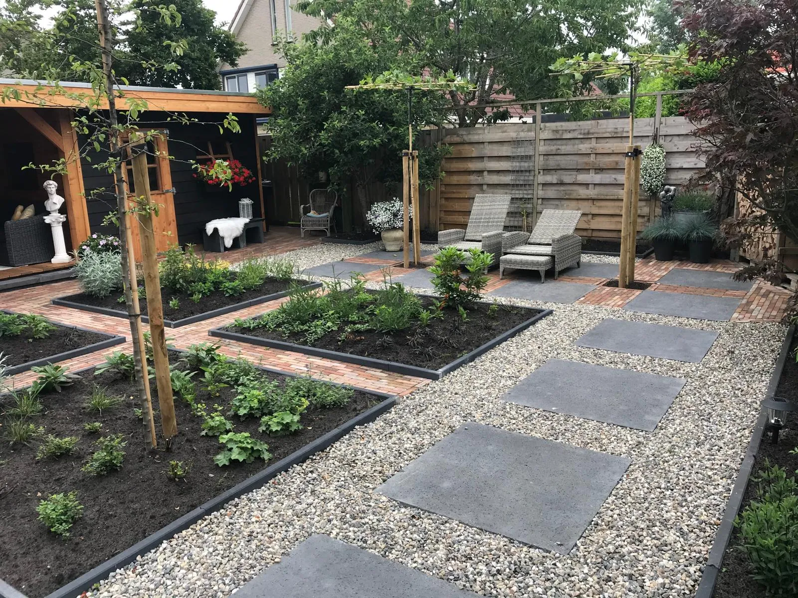 Moderne achtertuin met strak pad en bestrating, voorbeeld van tuinaanleg in Gorredijk / Friesland