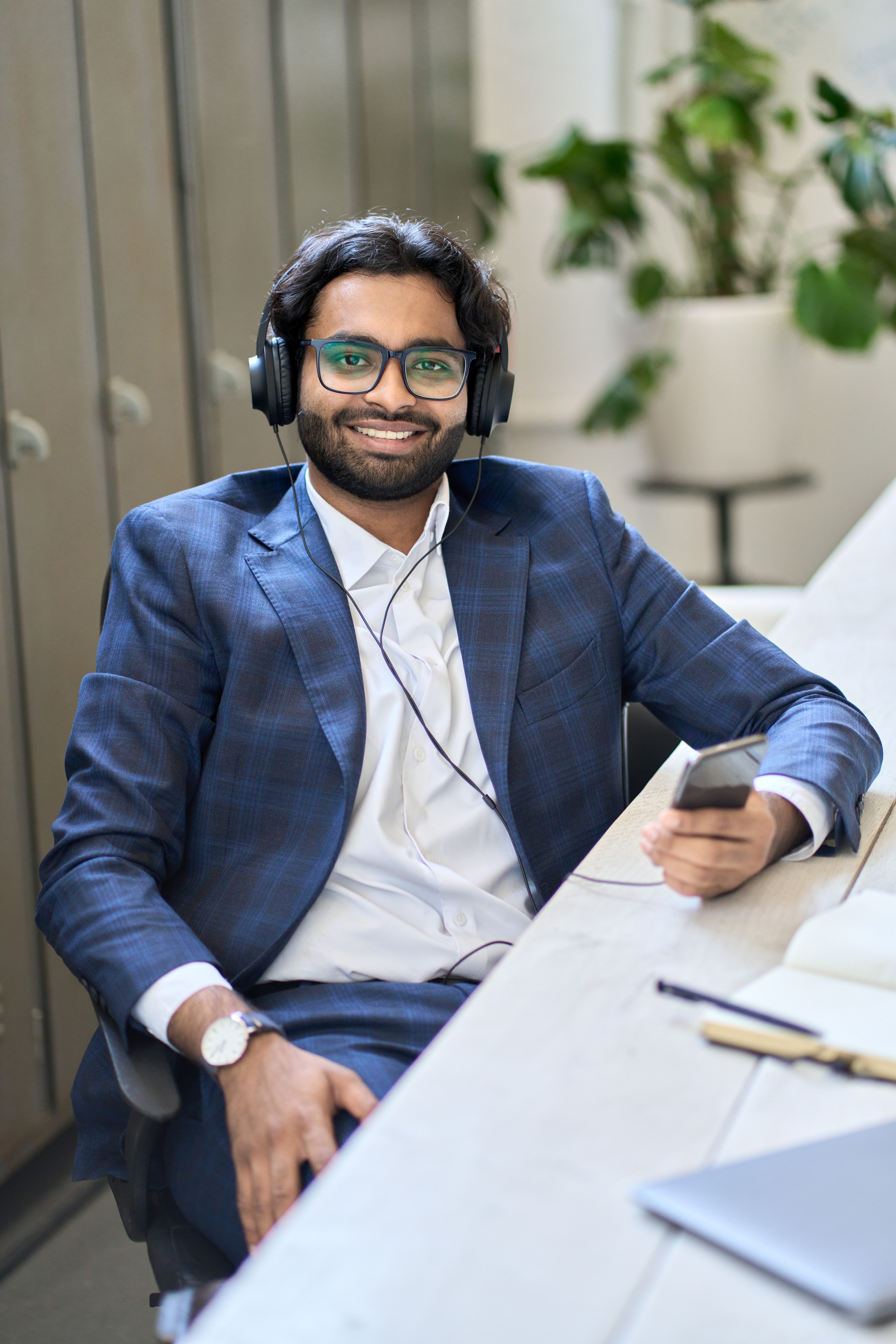 Professional male remote worker in a blue suit using headphones for online communication, showcasing efficient offshoring and remote workforce solutions for UK businesses.