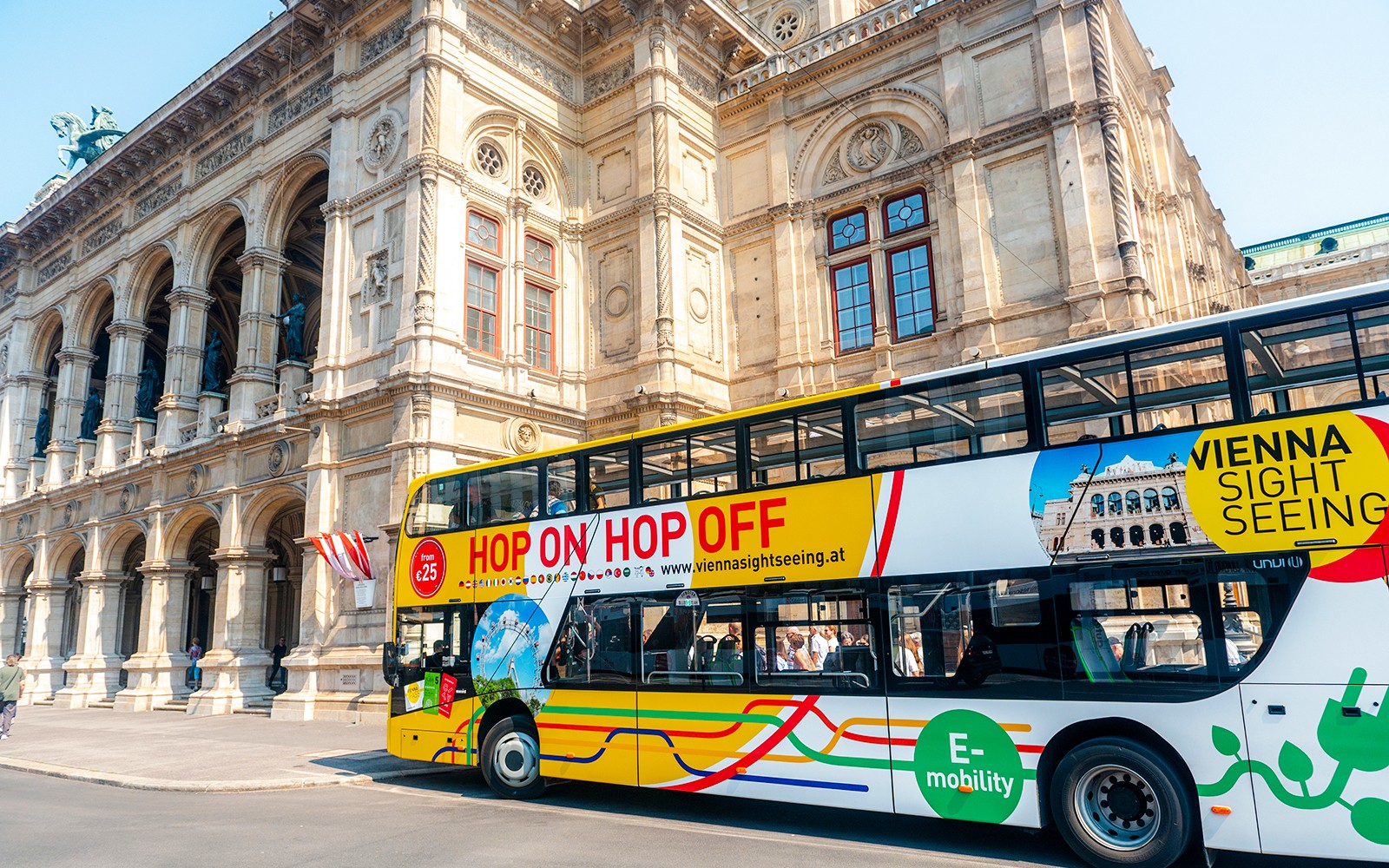 Bus wisata hop-on hop-off di depan bangunan bersejarah di Wina.
