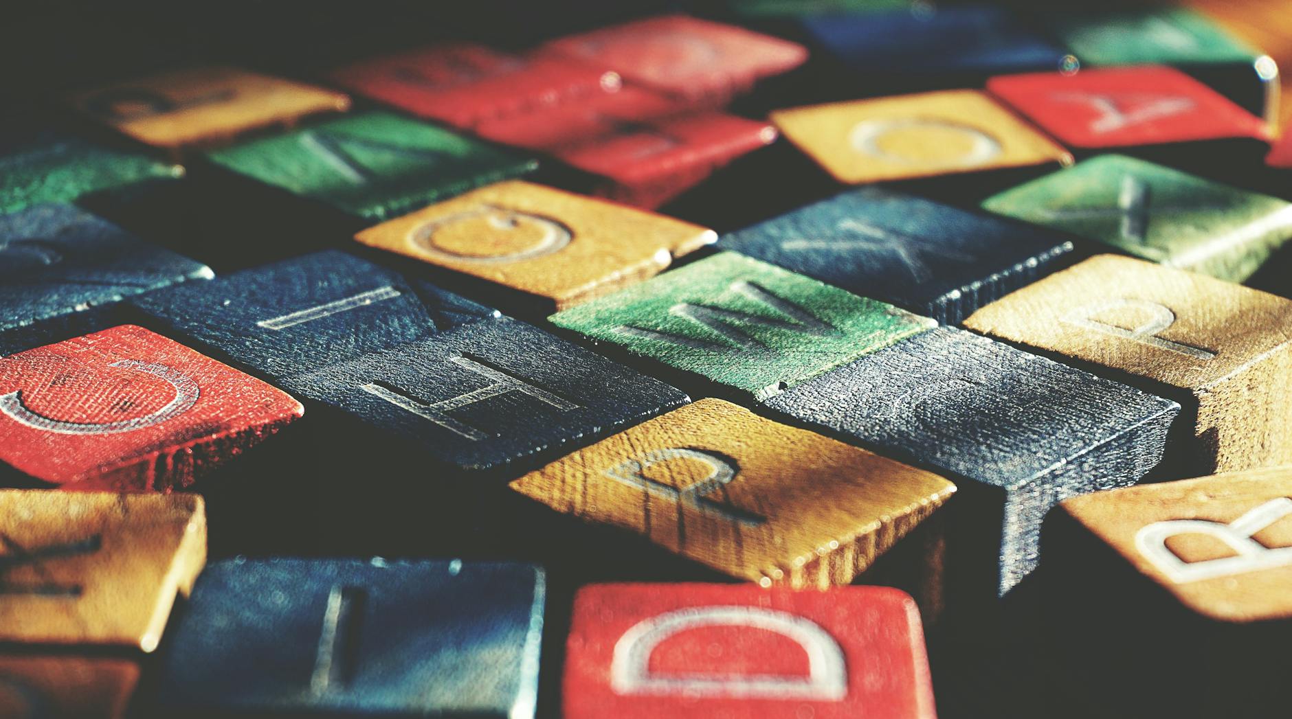 Close-up of a wooden alphabet puzzle next to several open pre reader books on a bright classroom table.
