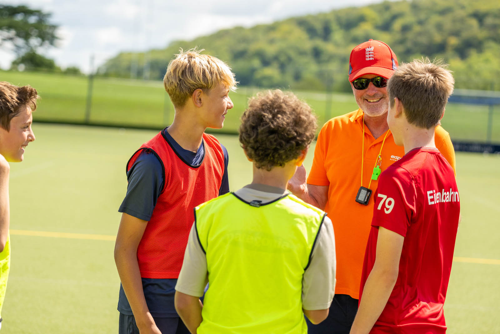 A hockey coach smiling while talking to his players.